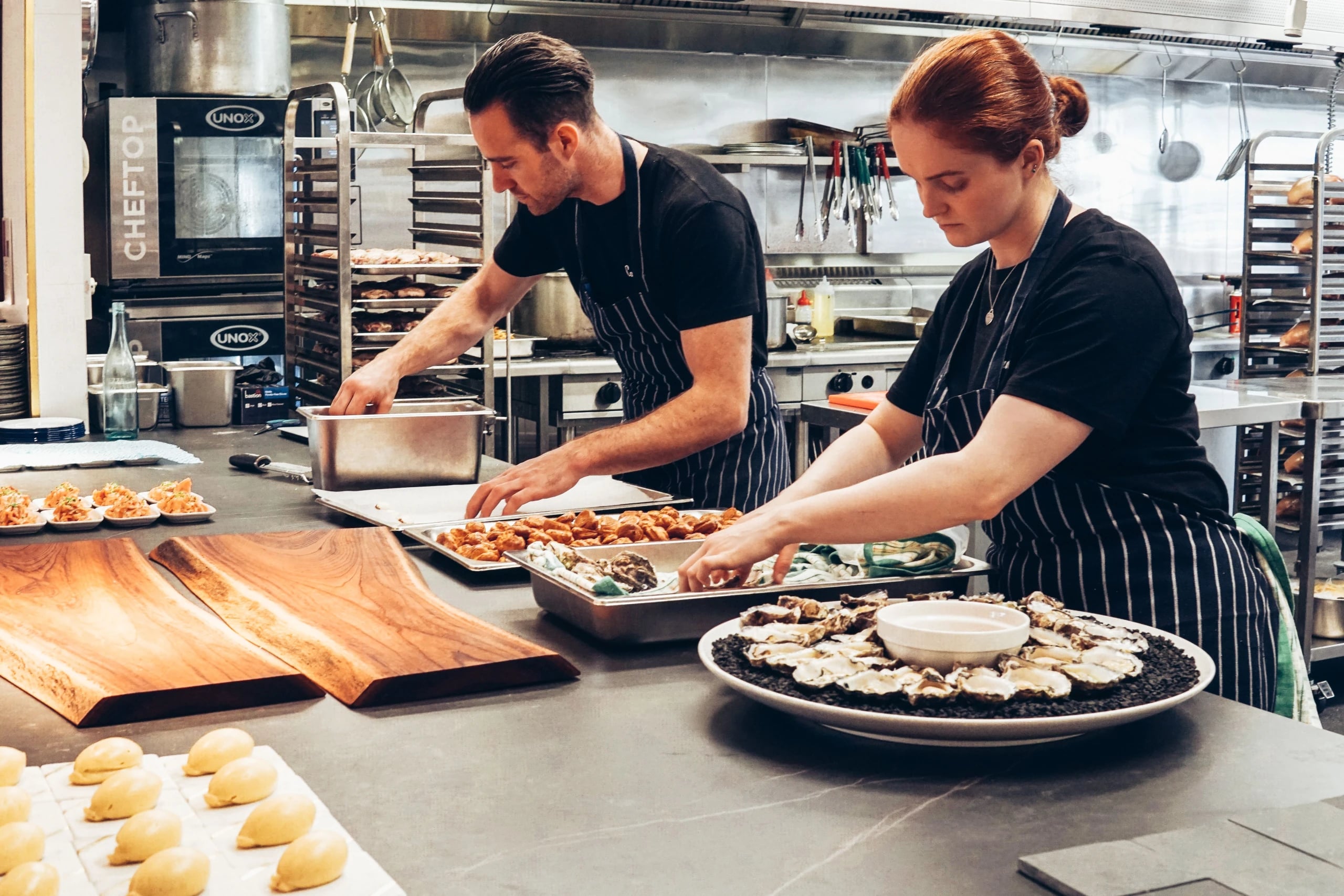 Two chefs preparing dishes together in a professional kitchen
