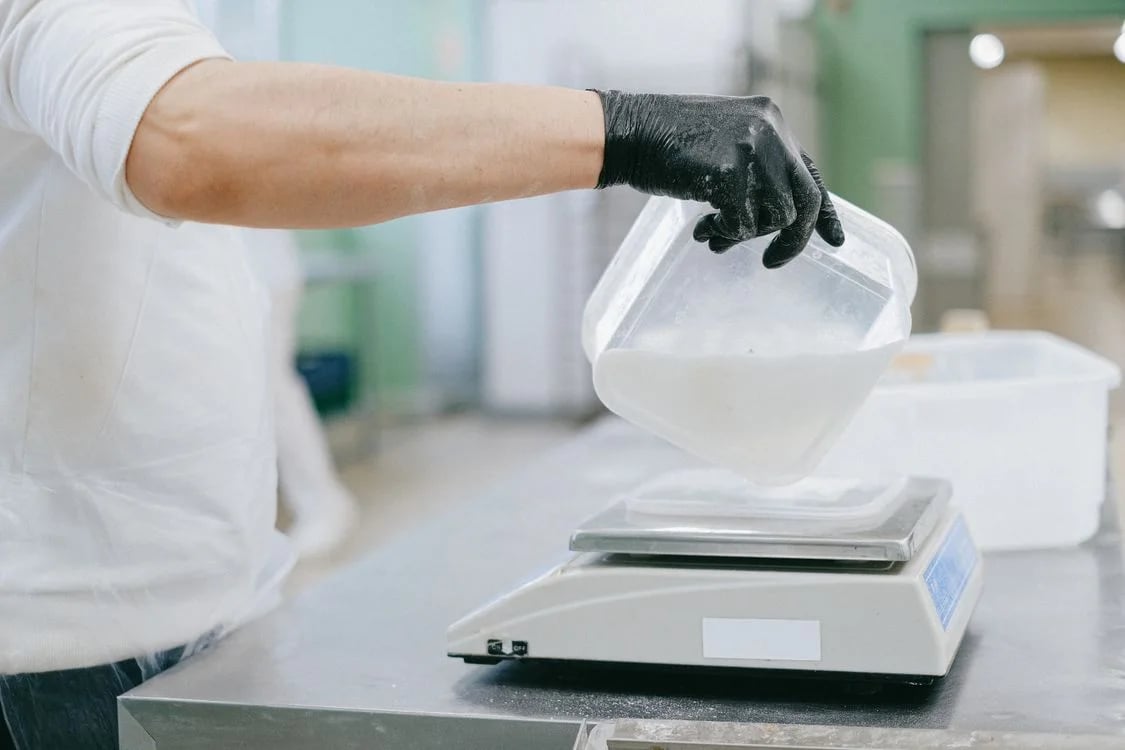 Chef carefully weighing ingredients on a digital kitchen scale